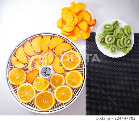 Drying oranges, kiwis and persimmons for the winter in a dryer. Preparing dry fruit slices, copy space for text, healthy snack Drying oranges, kiwis and persimmons for the winter in a dryer. Preparing dry fruit slices, copy space for text, healthy snack 124447702