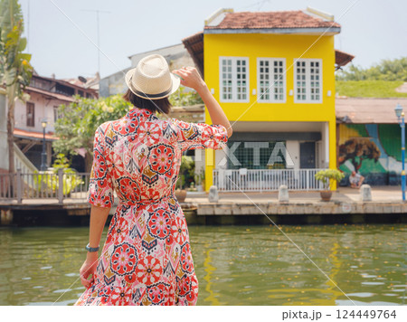 woman in dress and hat exploring vibrant streets of Malacca, Malaysia. 124449764
