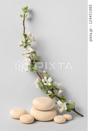 Wood slice podium and and blossoming branches of apple tree on gray background. Concept scene stage showcase for new product, banner, promotion sale, cosmetic, presentation. Spring concept Wood slice podium and and blossoming branches of apple tree on gray background. Concept scene stage showcase for new product, banner, promotion sale, cosmetic, presentation. Spring concept 124451985