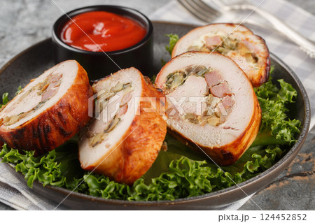 Delicious turkey fillet roll stuffed with bacon, onions and mushrooms served with ketchup close-up in a plate. Horizontal 124452852