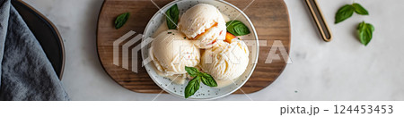 Peach ice cream scoops topped with crumbled biscuits and basil leaves, served in a bowl 124453453