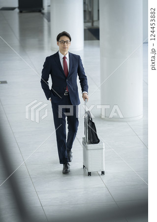キャリーケースを持って歩く40代のビジネスマン キャリーケースを持って歩く40代のビジネスマン 124453882