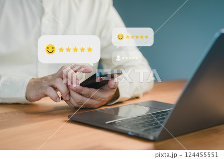 Person using a smartphone to leave a five-star review, with floating feedback icons and a laptop on a desk, symbolizing online reviews, testimonial and customer satisfaction. 124455551