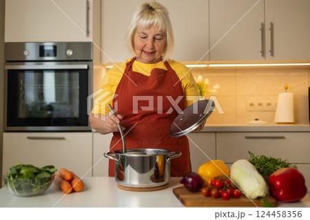 Cooking vegetables in a pot, stirring the ingredients with a spoon Cooking vegetables in a pot, stirring the ingredients with a spoon 124458356