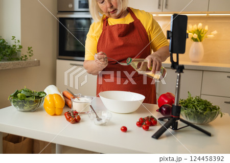 Senior Woman Adding Vinegar to a Bowl While Cooking in the Kitchen Senior Woman Adding Vinegar to a Bowl While Cooking in the Kitchen 124458392