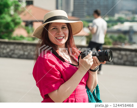 Smiling woman using a camera to take photo outdoors at the park. 124458468