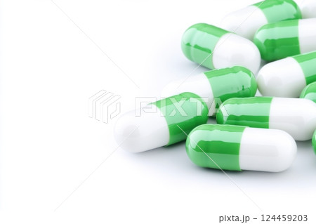 Green and white capsules scattered on a smooth light surface showcasing their vivid colors and unique design 124459203