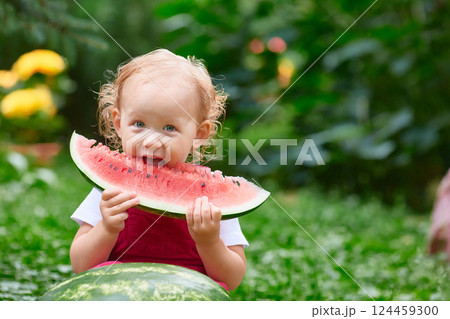 kid eats a big piece of watermelon on the street on a summer day kid eats a big piece of watermelon on the street on a summer day 124459300