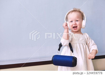 Girl listens to music sings and dances in headphones with a music speaker in her hands. Copy space Girl listens to music sings and dances in headphones with a music speaker in her hands. Copy space 124459778