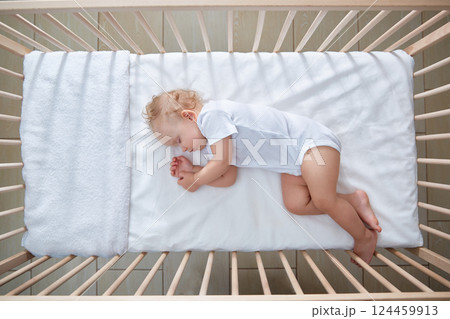 Toddler is sleeping in the crib. Top view. A cradle with a baby on a sunny day Toddler is sleeping in the crib. Top view. A cradle with a baby on a sunny day 124459913