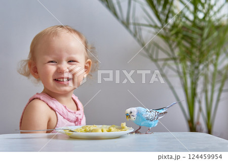 smiling child next to his pet budgie. 124459954