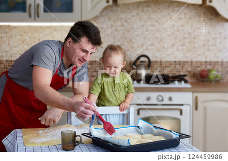 Father and child bake pies, cook food and have fun in the kitchen. Homemade food and a little helper. Happy parenthood 124459986