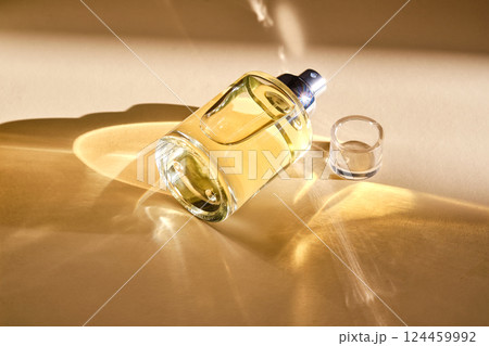 Perfume on a beige background in the rays of bright sun with beautiful highlights. Perfume on a beige background in the rays of bright sun with beautiful highlights. 124459992