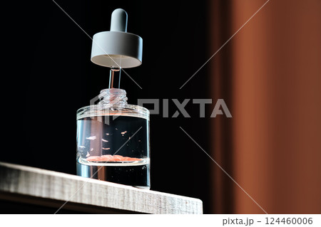 Serum bottle with petals on a dark background. Serum bottle with petals on a dark background. 124460006