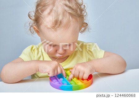 A curly-haired child grabs an anti-stress toy in the ass. Education of children with the help of popular games. A curly-haired child grabs an anti-stress toy in the ass. Education of children with the help of popular games. 124460068