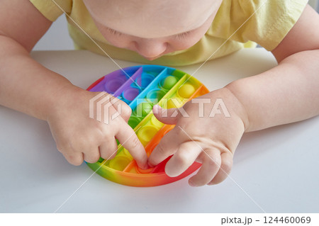 Anti stress toy Pop It. Close up Child Playing With The Pop It Fidget Toy. Happy childhood, popular educational games. Anti stress toy Pop It. Close up Child Playing With The Pop It Fidget Toy. Happy childhood, popular educational games. 124460069