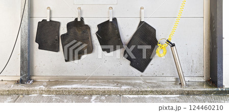 Black rubber car mats hanging on steel pegs to dry in carwash after being washed Black rubber car mats hanging on steel pegs to dry in carwash after being washed 124460210