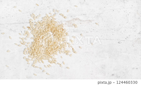White sesame - Sesamum indicum - seeds on white stone like board, view from above, space for text right side White sesame - Sesamum indicum - seeds on white stone like board, view from above, space for text right side 124460330