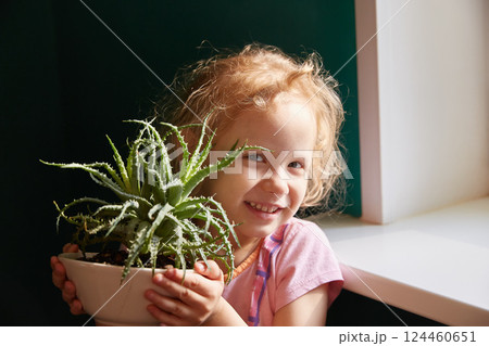 A smiling girl holds a rare aloe flower in a pot. A smiling girl holds a rare aloe flower in a pot. 124460651
