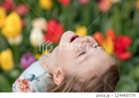 Happy girl laughs in a park with the tulips field 124460770