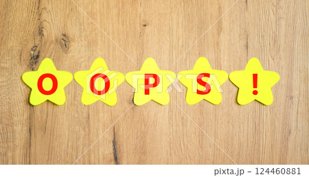 Oops symbol. Concept word Oops on beautiful yellow paper stars. Beautiful wooden table wooden background. Business lifestyle oops concept. Copy space. Oops symbol. Concept word Oops on beautiful yellow paper stars. Beautiful wooden table wooden background. Business lifestyle oops concept. Copy space. 124460881