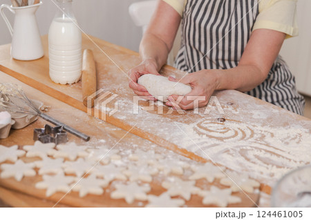 Senior woman cooking in kitchen, hands close up. Older mature lady grandmother hands knead dough bake cookies. Old grandma cook homemade food. Household housewife housework concept 124461005