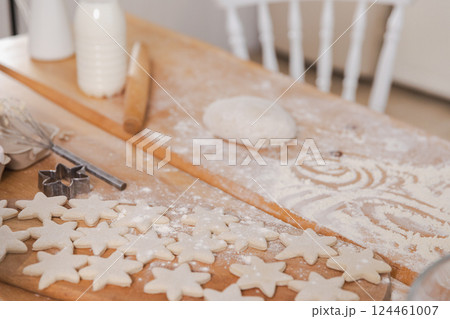 Star shaped raw cookies ready to bake. Baking sheet uncooked biscuits homemade cakes and ingredients on kitchen table. Homemade food preparing process. Household housewife housework concept Star shaped raw cookies ready to bake. Baking sheet uncooked biscuits homemade cakes and ingredients on kitchen table. Homemade food preparing process. Household housewife housework concept 124461007