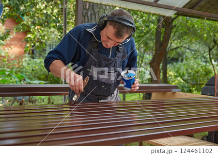 A man in a work suit paints metal pipes. A man in a work suit paints metal pipes. 124461102