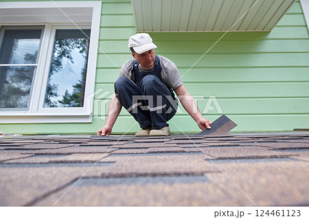 A worker lays soft tiles on the roof of the terrace 124461123