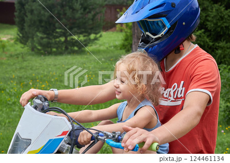 A little girl on a motorcycle without a helmet. The concept of children's safety on the roads. A little girl on a motorcycle without a helmet. The concept of children's safety on the roads. 124461134