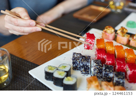 A woman's hand takes Japanese fish rolls 124461153