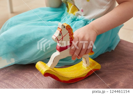 A faceless child girl is playing a wooden horse 124461154