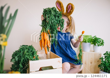 Cute little child girl wearing bunny ears holding fresh bunch of carrots 124461171