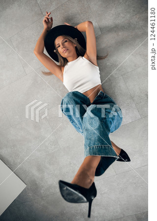 Stylish woman poses in casual outfit on modern floor during bright daylight 124461180
