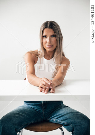Woman sitting at a table with a neutral expression in a modern interior space 124461183