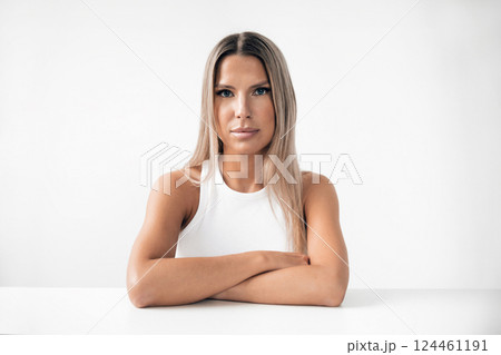 Confident woman poses with crossed arms against a minimalistic white background Confident woman poses with crossed arms against a minimalistic white background 124461191