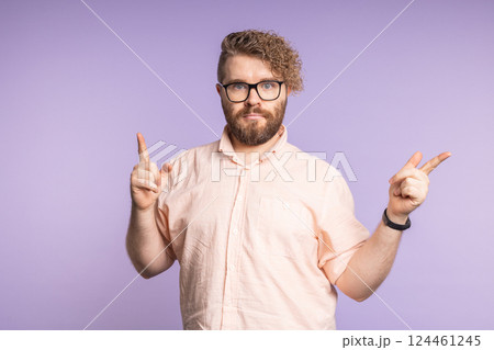 Young man pointing fingers in opposite directions with serious face. Decision making, options, and visual emphasis on choice Young man pointing fingers in opposite directions with serious face. Decision making, options, and visual emphasis on choice 124461245