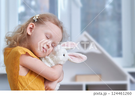 A girl hugs a white rabbit toy. Close-up. The concept of reconciliation and love. A girl hugs a white rabbit toy. Close-up. The concept of reconciliation and love. 124461260