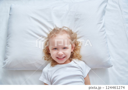 Smiling cute girl on a white pillow. Copy space 124461274