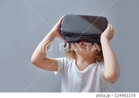 A curly-haired child looks into virtual reality glasses. A curly-haired child looks into virtual reality glasses. 124461278