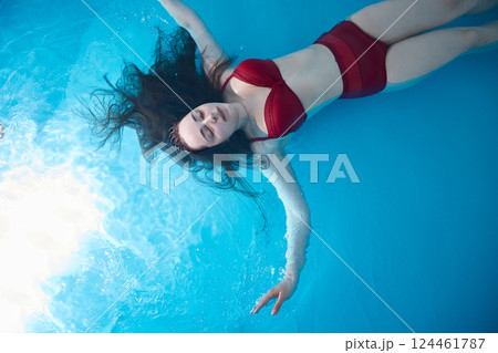 Portrait of woman floating in swimming pool. Relaxation and spa therapy. Copy Space. 124461787