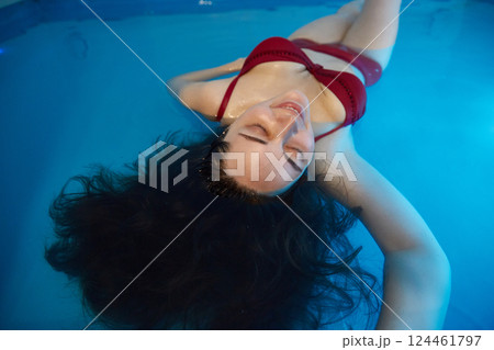 Portrait of a relaxed young woman swimming in the salt water of the pool. Floating concept. Portrait of a relaxed young woman swimming in the salt water of the pool. Floating concept. 124461797