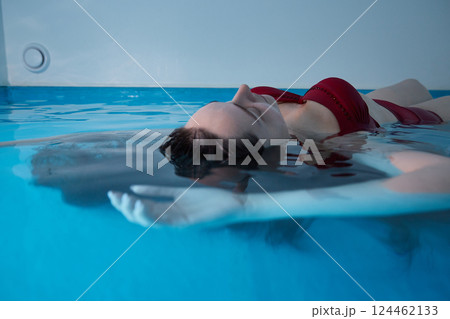 A young woman is swimming relaxed in a small pool. 124462133