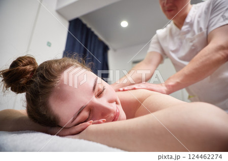 Body massage procedure. A woman in a spa salon. The masseur is working on her back Body massage procedure. A woman in a spa salon. The masseur is working on her back 124462274