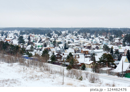 A serene village is enveloped in a soft layer of snow, with charming homes peeking through the white landscape 124462476