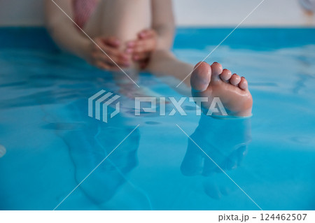 Women's feet in a saltwater pool. Water spa treatments in the sanatorium. 124462507