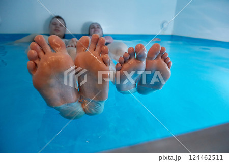 Male and female legs side by side in the pool in water with sea salt. Floating concept. Copy space Male and female legs side by side in the pool in water with sea salt. Floating concept. Copy space 124462511