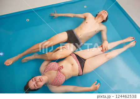 Man and a woman lie relaxed in a therapeutic wellness pool with salt water. Top view 124462538