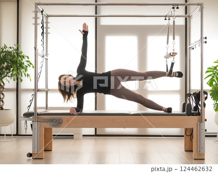 Woman doing Pilates on reformer. Woman doing Pilates on reformer. 124462632