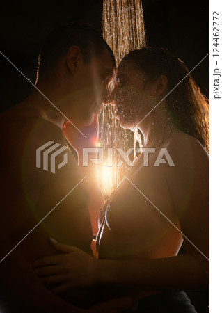 Couple sharing a romantic moment under a shower with soft lighting at night 124462772